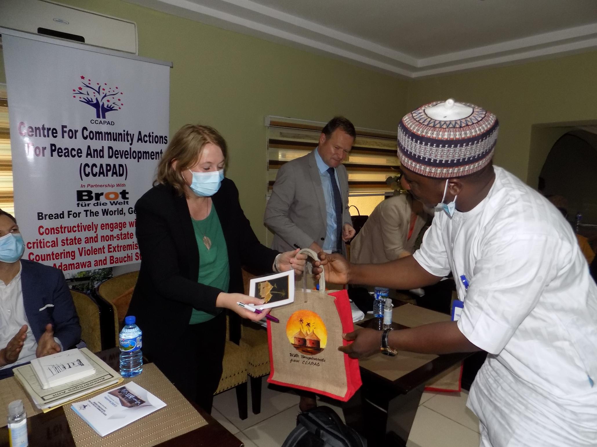 CCAPAD volunteer smiling while holding a Peace Begins with a Smile poster